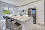 Luxurious kitchen features a white marble, waterfall island -w/ four counter stools-